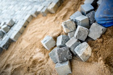 Construction worker placing cobblestone, granite stone on pavement