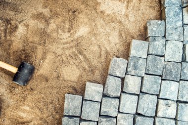 Construction tools and details, pavement installing and rocks. Granite stones laying on sand, making of pavement