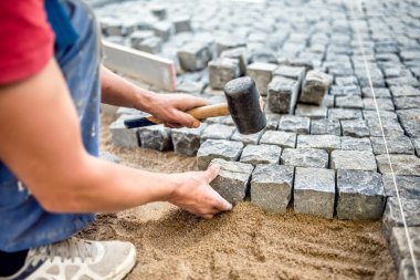 Construction worker installing stone blocks on pavement, street or sidewalk construction works clipart