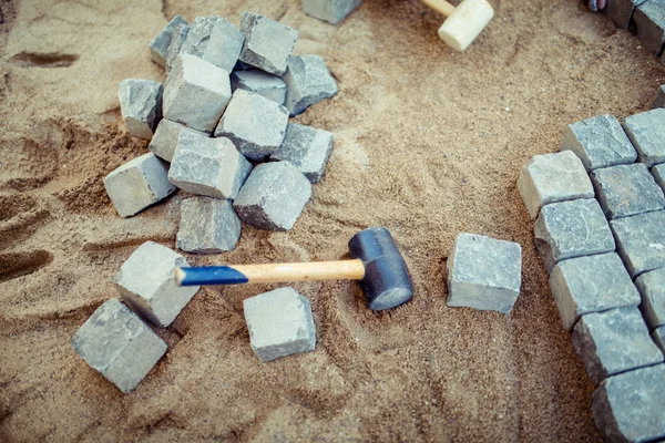 Pavimenti in pietra, su sabbia, con utensili e dettagli costruttivi. Posa del selciato pavimentazione per terrazza all'aperto — Foto Stock
