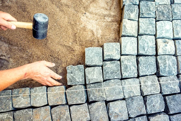 Industrial worker installing pavement rocks, cobblestone blocks on road pavement — Stock Image Industrial worker installing pavement rocks, cobblestone blocks on road pavement Royalty Free Stock Images