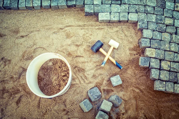 Construction of pavement details, cobblestone pavement, stone blocks and rubber hammers on construction site — Stock Image Construction of pavement details, cobblestone pavement, stone blocks and rubber hammers on construction site Royalty Free Stock Photos