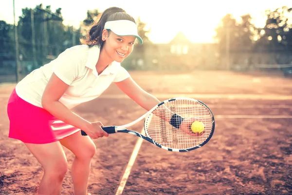 美しいブルネットの少女は、ラケット、ボール、スポーツ用品とテニスします。体操服と笑みを浮かべてテニスコート上で美しい女性の肖像画間近します。 — ストック写真