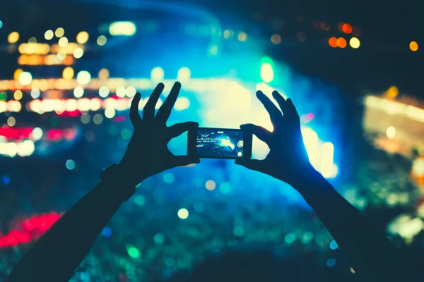 Silhuetten av en man tar bilder på festival konsert. Konsert lampor och prestanda av festivalens artister. — Stockfoto