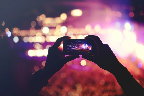 Silueta de manos grabando vídeos en el concierto de música. Concierto de música pop con luces, humo y mucha gente — Foto de Stock