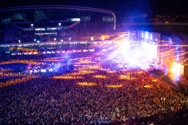 Pessoas felizes batendo palmas no concerto noturno, festejando e levantando as mãos para o artista no palco. Vista aérea desfocada da multidão de concertos — Fotografia de Stock