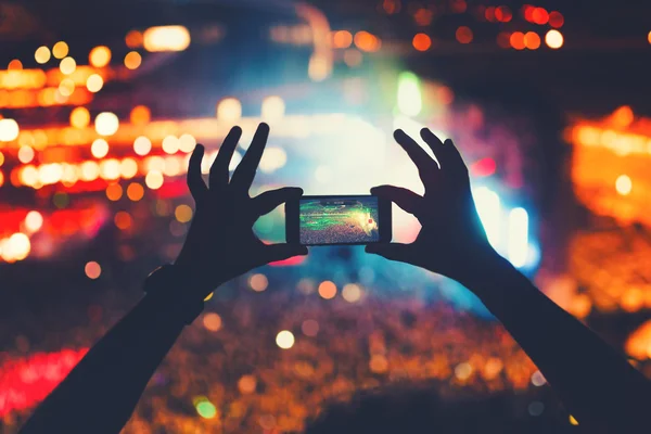 Joven hipster tomando fotos y videos en concierto. Estilo de vida moderno con smartphone y fiestas . Imagen De Stock