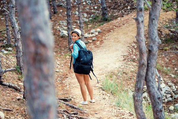 Жінка з рюкзаком ходить по горах, ходить і біжить по лісах і пагорбах. Щаслива жінка, готова до пригод, досліджуючи природу — стокове фото