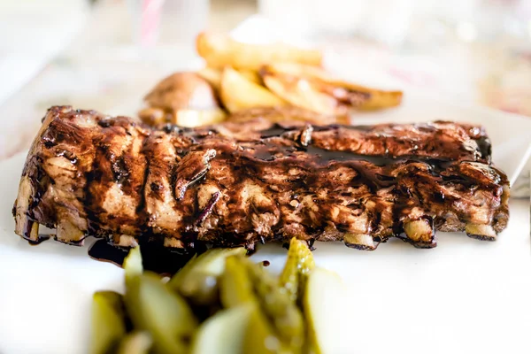 Huvudrätten på fancy restaurang - amerikanska revbensspjäll på barbeque sås med pickels och potatis — Stockfoto