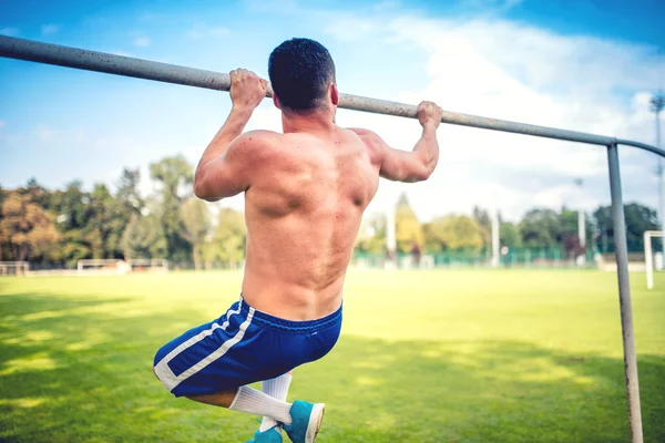 Athletic fitness trainer, basketball and football player training out on the field. Chinups and Pullups training — Stock Photo, Image