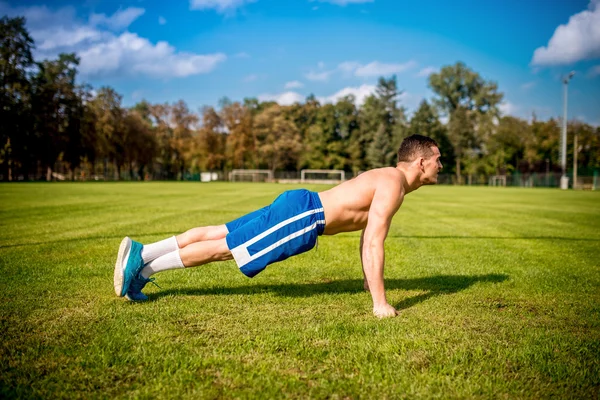 Entrenador de fitness haciendo ejercicio en el campo de fútbol. Entrenamiento saludable en gimnasio al aire libre —  Fotos de Stock