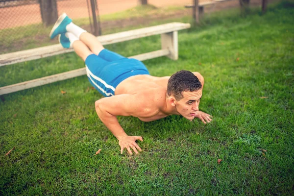 Bell'uomo che fa flessioni nel parco, bodybuilding e formazione. Concetto di fitness con uomo senza maglietta all'aperto, facendo esercizi — Foto Stock