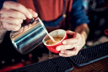 Barista uzun kahve sütlü Latte sanat oluşturma. Kupa kahve sanat latte. Barmen yağan taze kahve