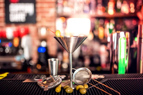 Napój alkoholowy na kontuar barowy. Suche martini z lodem i oliwki, podawane na zimno w restauracji, barze lub pubie. — Zdjęcie stockowe