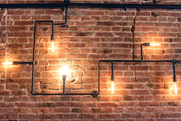 Diseño interior de pared vintage. Diseño rústico, pared de ladrillo con bombillas y tuberías, interior de barra de baja iluminación — Foto de Stock