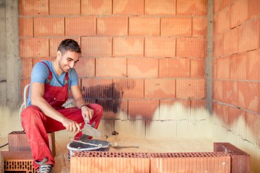 İnşaat mason işçisi, tuğla duvarlar spatula ve harç ile bina çimento