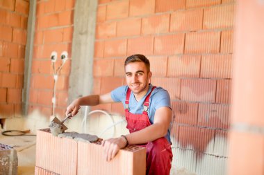 Çimento, harç ve macun bıçak ile tuğla duvarlar inşa işçisi gülümseyerek. Harçla duvarları oluşturmak için mason