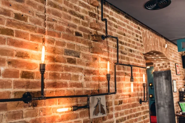 Rustykalne ściany restauracji, lampy do zabytkowych wnętrz, rury metalowe i żarówki — Zdjęcie stockowe