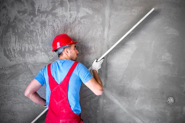 Intonaco al lavoro in cantiere, livellamento delle pareti e verifica della qualità. Lavoratore industriale in cantiere — Foto Stock