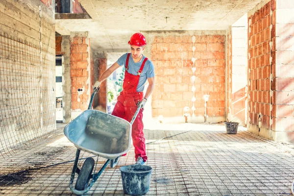 Werknemer met lege kruiwagen op de bouwplaats — Stockfoto