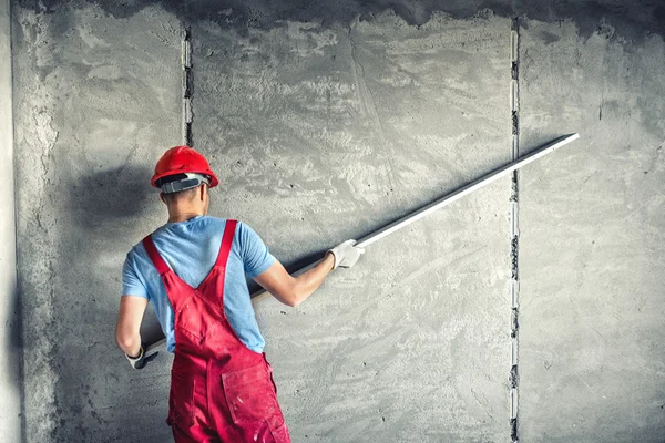 Trabajador industrial con herramientas de enlucido que renueva una casa. constructor trabajador enlucido fachada edificio industrial con nivelador —  Fotos de Stock