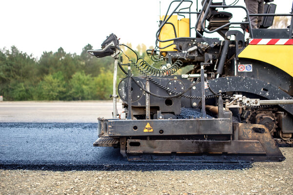 industrial pavement truck laying fresh asphalt on construction site, asphalting