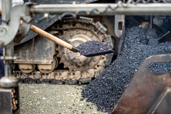 Industrial worker, handyman using shovel for carrying asphalt at road construction works — Stock Photo, Image