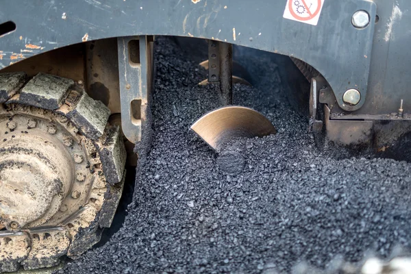 Close-up details of industrial machinery working with asphalt, mixing bitumen with hot asphalt, layering on the road surface — Stock Photo, Image