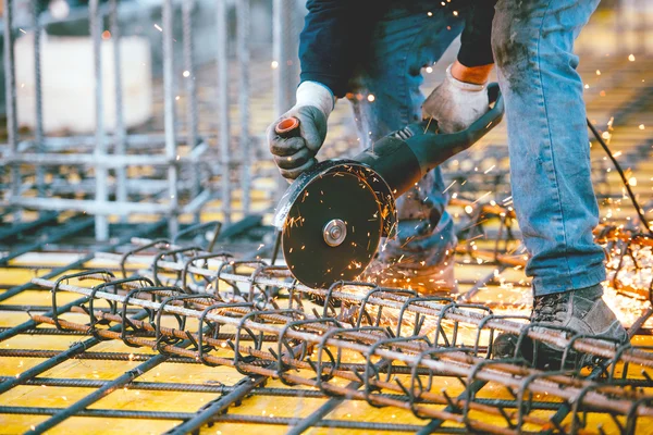 Worker using an angle grinder for cutting steel, making sparks and debris — Stock Photo, Image