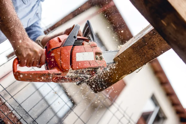 Trabalhador que utiliza uma motosserra para o corte de madeira, material de construção, corte e corte de toras — Fotografia de Stock