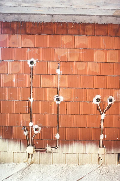 Casa canteiro de obras com materiais energeticamente eficientes, isolamento térmico e paredes de tijolo com plugues e tubos de eletricidade — Fotografia de Stock