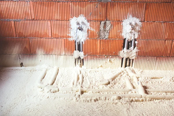 Thermo insulation with spray foam, brick walls and pipes at construction site — Stock Image Thermo insulation with spray foam, brick walls and pipes at construction site Stock Photo