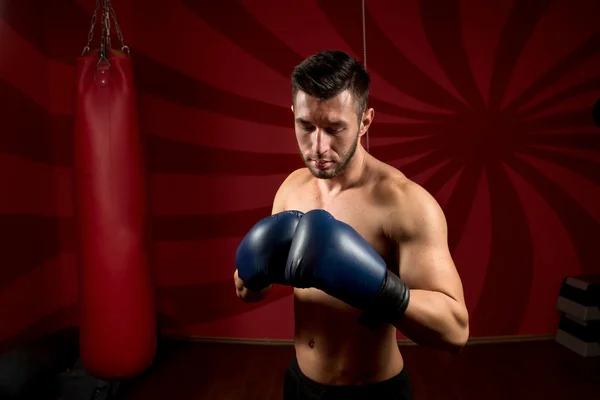 Boxeur sportif avec des gants et torse nu posant dans la salle de gym — Photo