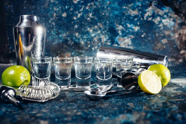 Алкогольные стопки текилы или крепкого напитка в маленьких бокалах, с гарниром из лайма, готовым к подаче — стоковое фото