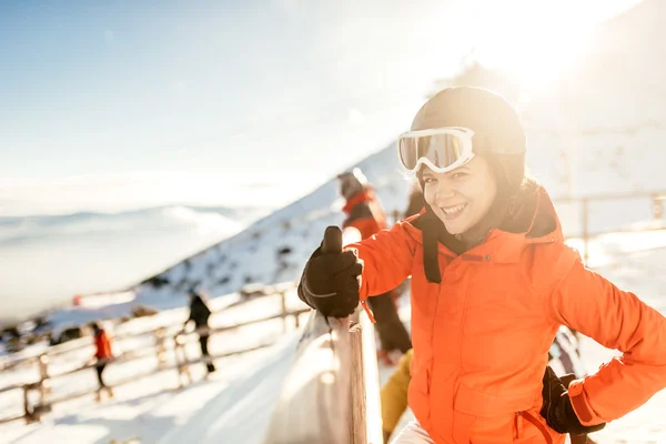 Woman skier on slopes. Portrait of young woman smiling in skiing equipment, wearing goggles and helmet — Stock Photo, Image