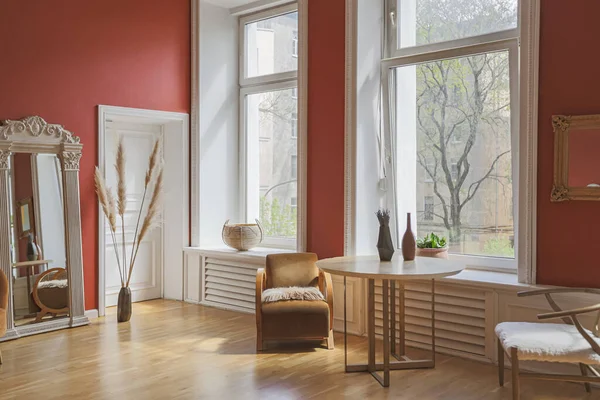 antique vintage interior in 19th century style living room with bright red walls, wood floor and direct sunlight inside the room.