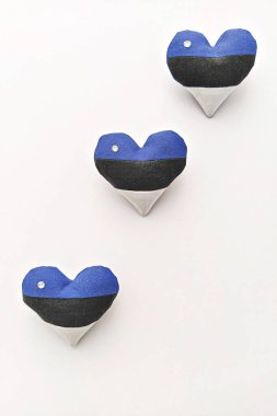 Beyaz arka planda, Estonya bayrağı renginde üç el yapımı kalp. Estonya 'nın bağımsızlığını kutluyoruz