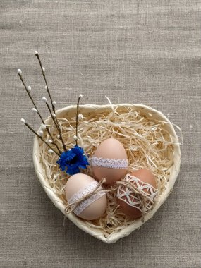 Paskalya kompozisyonu dantelli Paskalya yumurtaları hasır sepette keten arka planda.