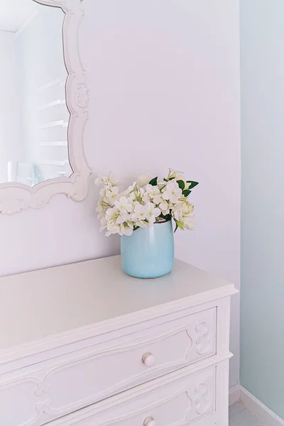 Speil i utskåret treramme og vase med blomster i lysrommet, vintage interiør. – stockfoto
