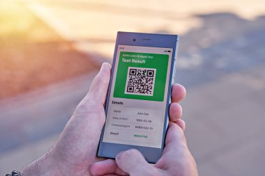 Elinde akıllı telefon tutan adam mobil uygulama negatif COVID-19 ekspres test sonuçlarını gösteriyor. Dokunulmazlık aşısı pasaportu, aşı sertifikası, yeni normal seyahat için sağlık pasaportu