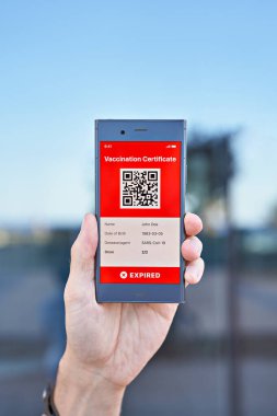 Elli adam elinde Covid-19 için süresi geçmiş dijital yeşil aşı sertifikasını gösteren bir akıllı telefon tutuyor. Dokunulmazlık aşısı pasaportu, aşı sertifikası, yeni normal seyahat için sağlık pasaportu