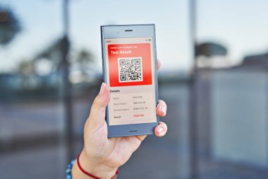 Elli kadın akıllı telefon tutuyor ve Covid-19 uygulamasının pozitif sonuçlarını gösteriyor. PCR testi, mobil uygulamanın dijital sonucu