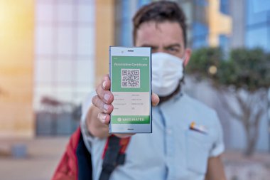 Elinde akıllı telefon tutan adam Covid-19 için geçerli dijital yeşil aşı sertifikası taşıyor. Dokunulmazlık aşısı e-pasaport, aşı sertifikası, yeni normal seyahat için sağlık pasaportu.