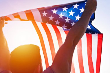 Amerikan bayrağını açık mavi gökyüzüne sallayan bir adamın yükselişinin alçak açılı görüntüsü. Amerika Birleşik Devletleri 'nin bağımsızlık günü. Amerikan vatanseverlik kavramı