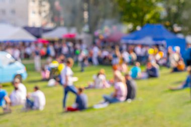 Bulanık bir grup insan açık hava pikniğinin ve açık hava festivalinin keyfini çıkarıyor.