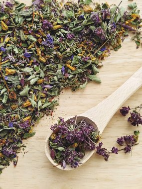 Nane, kekik ve çiçek ile harmanlanmış kurutulmuş bitki çayı, renkli yapraklar ve tahta tahtada kaşık ile taç yaprakları, mis kokulu doğal görünüş.