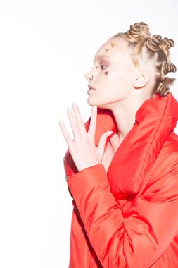 Genç bir kız elini yüzüne yaklaştırıyor ve profilden bakıyor. Yüzünde çiviler, burnunda piercingler. Gençlik alt kültürü