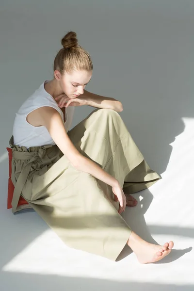 Girl Sitting Pillow She Looks Her Bare Foot She Wearing — Stock Photo, Image