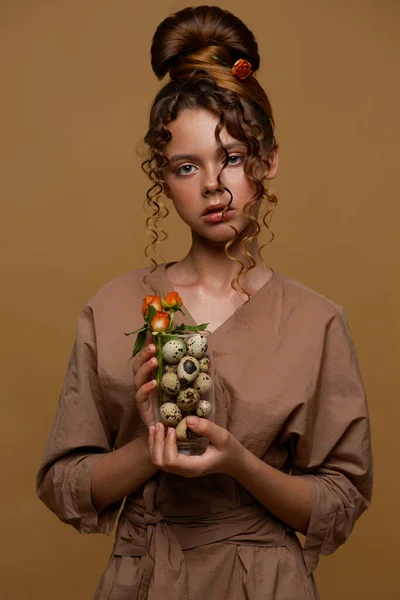 一个少女的画像 在玫瑰的头发上 她手里拿着一只装有锯蛋和一束鲜花的杯子 不同寻常的发型 — 图库照片
