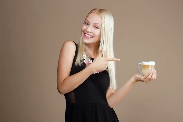Šťastný, blondýnka poukazuje na šálek kávy — Stock fotografie